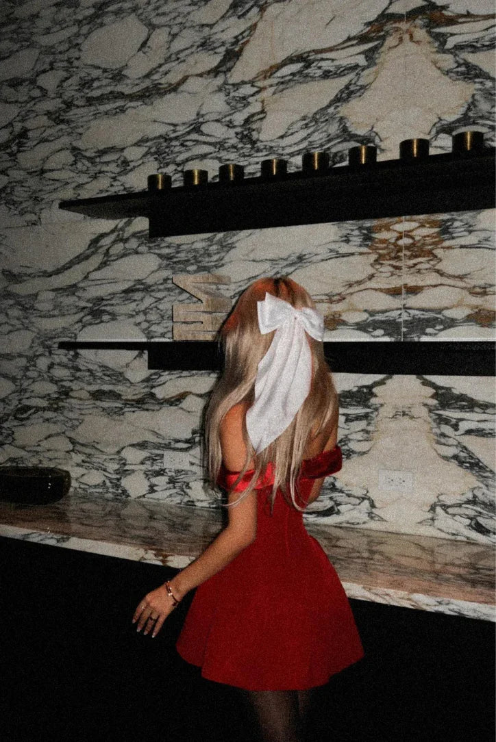 Robe de soirée rouge, épaules dénudées, en satin fluide, avec une coupe ajustée et un drapé élégant.