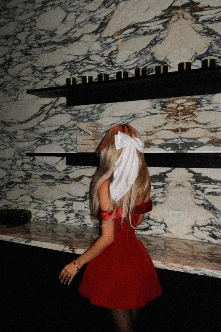 Robe de soirée rouge, épaules dénudées, en satin fluide, avec une coupe ajustée et un drapé élégant.