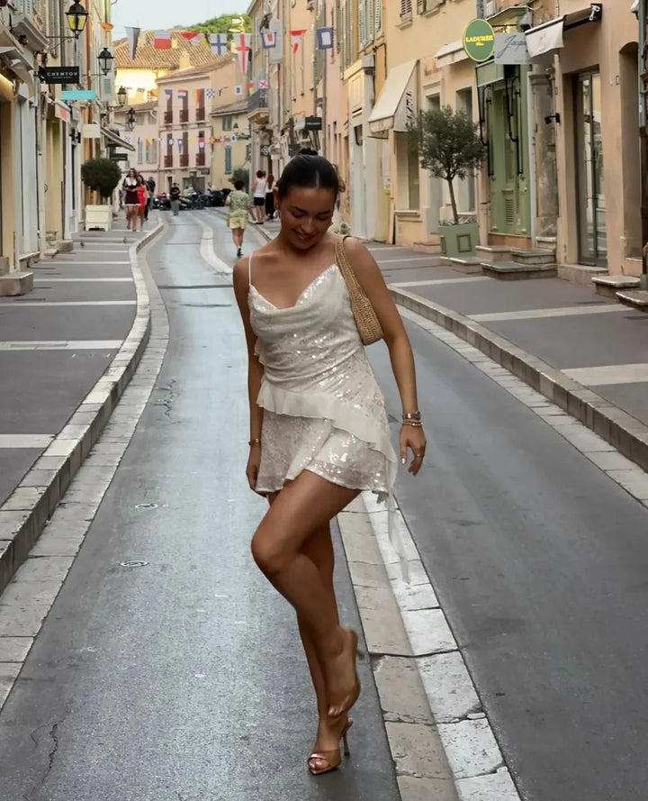 Robe été blanche pour femme, ornée de sequins, en tissu léger avec des bretelles fines et une coupe estivale fluide.