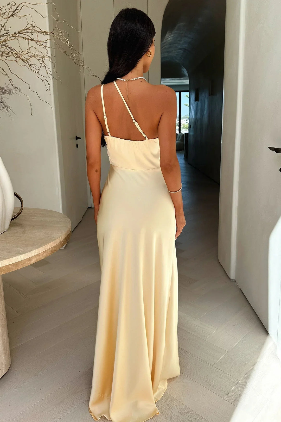 Robe longue asymétrique beige en tissu léger, avec une fente élégante et un décolleté discret pour un look stylé.