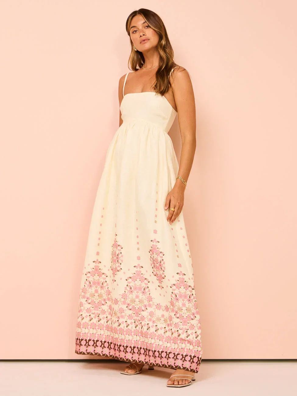 Robe longue blanche en coton, motifs floraux colorés, ourlet détaillé et bretelles fines, parfaite pour l'été.