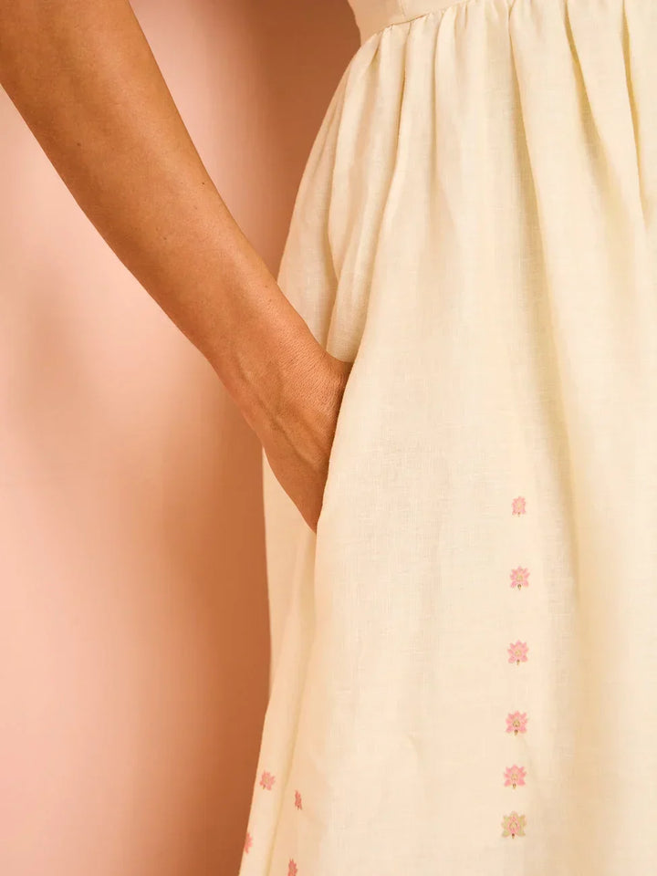 Robe longue blanche en coton avec motifs floraux, ourlet détaillé et bretelles fines, idéale pour l'été.