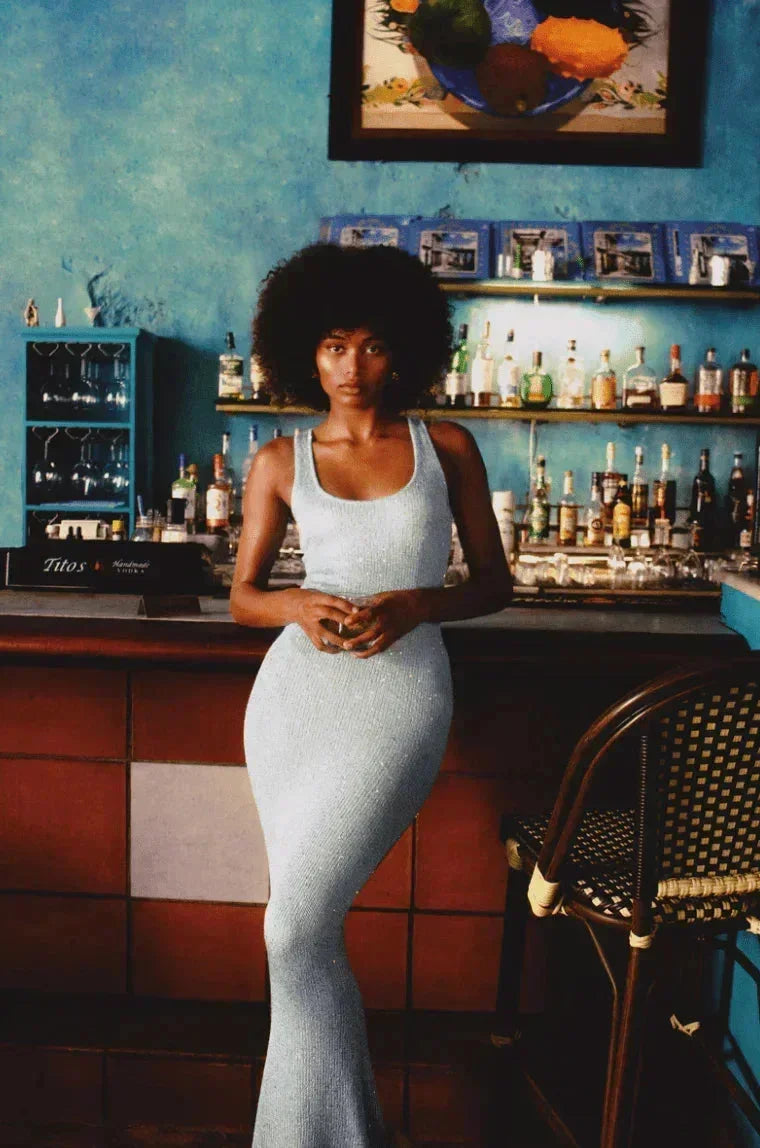 Robe longue sans manches en tissu bleu glacé, ajustée à la taille, offrant une coupe élégante et fluide.