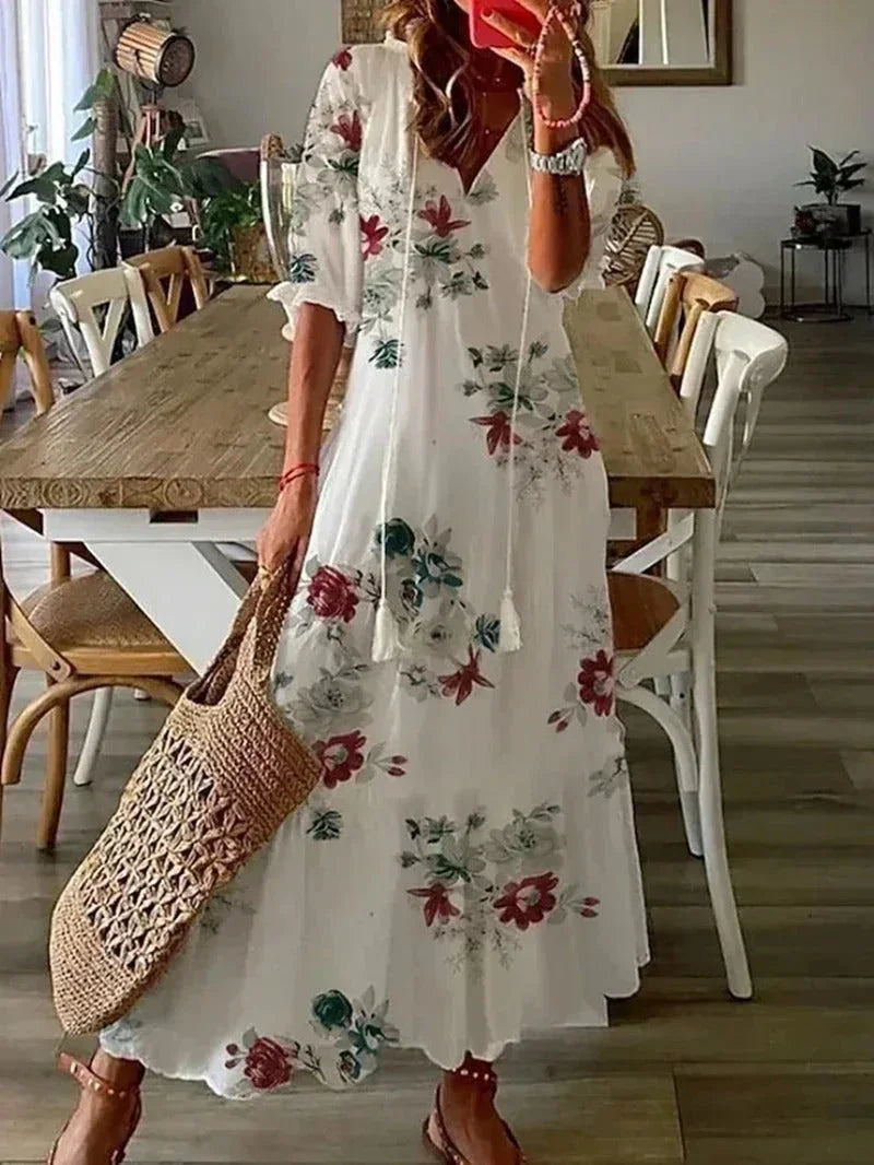 Robe longue femme blanche à col en V, en tissu léger, ornée de motifs floraux colorés, idéale pour les journées ensoleillées.