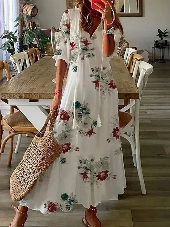 Robe longue femme blanche à col en V, en tissu léger, ornée de motifs floraux colorés, idéale pour les journées ensoleillées.