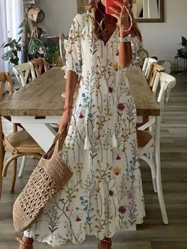 Robe longue femme à col en V, motifs floraux, en tissu léger et fluide, disponible en plusieurs couleurs.