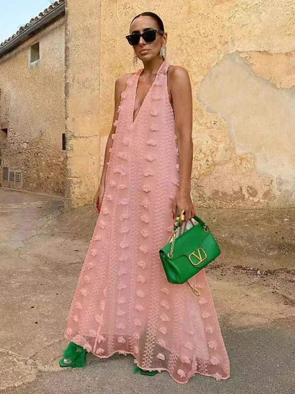 Robe longue femme en rose avec col halter, détails floraux et tissu léger, parfaite pour les journées ensoleillées.