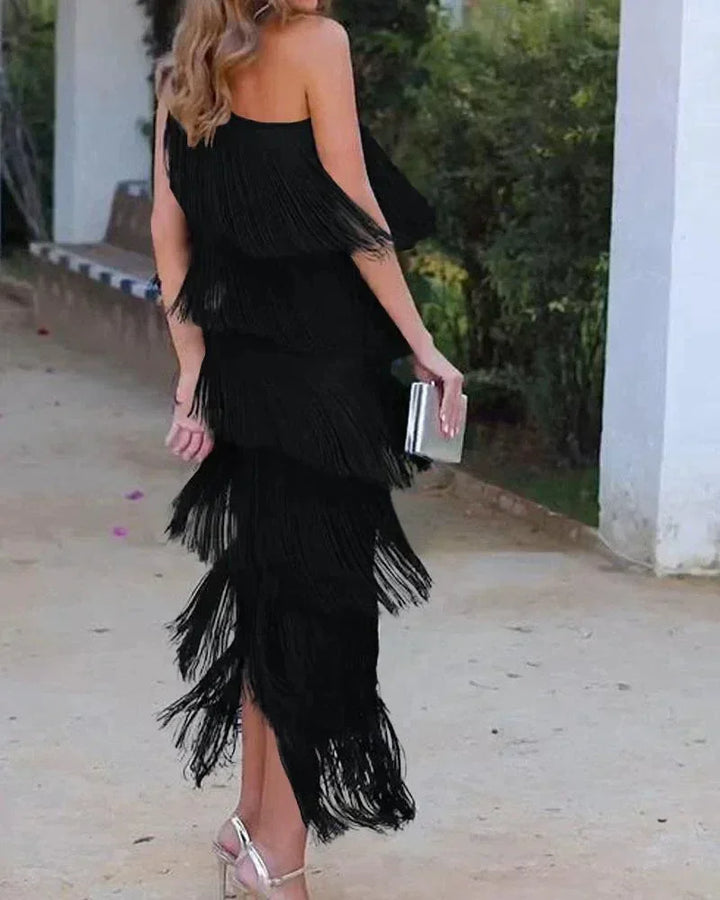 Robe longue femme en tissu léger avec franges et encolure asymétrique, idéale pour une soirée estivale.