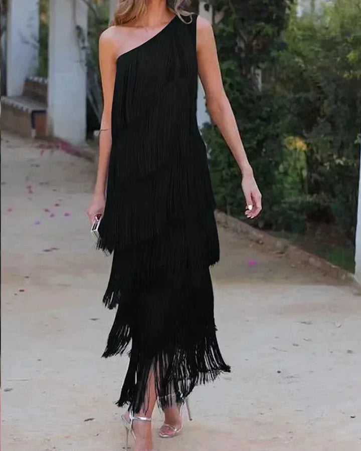 Robe longue femme en noir avec franges et encolure asymétrique, en tissu léger et fluide pour un look élégant.