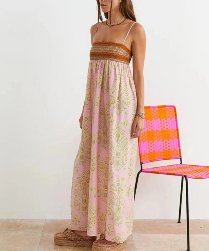 Robe longue rose boho à bretelles avec motifs estivaux, en tissu léger et fluide idéal pour les journées ensoleillées.
