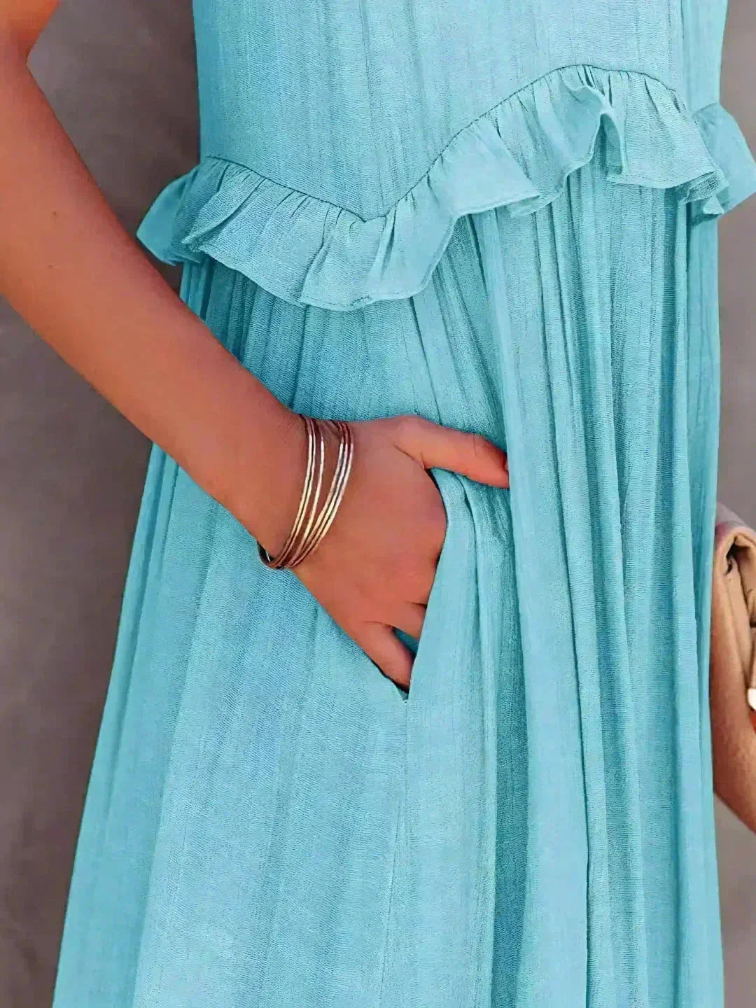 Robe longue sans manches en tissu léger, décorée de volants superposés pour un look élégant et fluide.