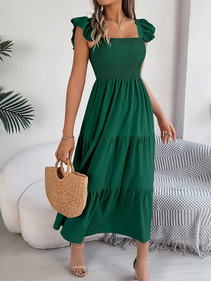 Robe longue femme smockée en vert, avec volants délicats et manches courtes, fabriquée en tissu léger et confortable.