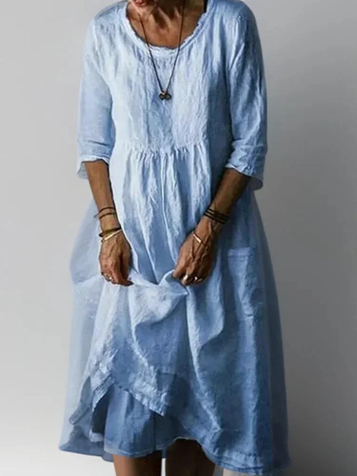 Robe longue bleue en tissu fluide, à volants, col en V et manches 3/4, idéale pour une tenue décontractée.
