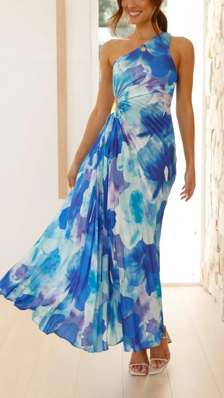 Robe longue bleue à une épaule, en tissu léger, avec un motif floral et des plis pour un look d'été élégant et aéré.
