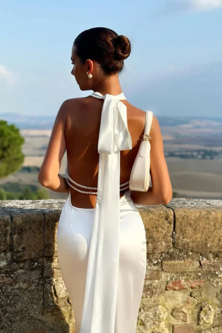 Robe longue blanche en tissu léger, dos ouvert avec des détails en perles, idéale pour une soirée d'été élégante.
