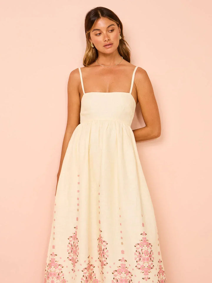Robe longue crème en coton, broderie florale délicate et bretelles fines, parfaite pour les journées d'été.