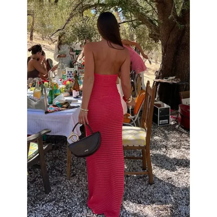 Robe maxi en crochet rose ornée de fleurs oranges, offrant un style bohème avec sa matière légère et aérienne.