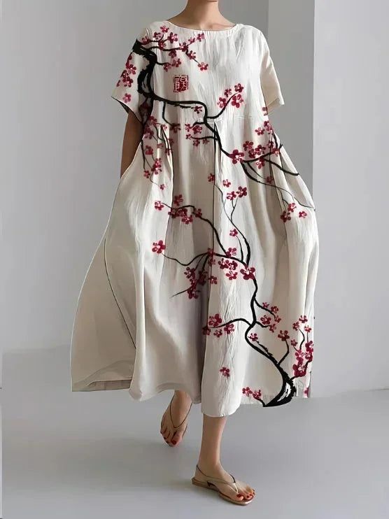 Robe maxi ample à fleurs cerisier, manches courtes, en viscose douce, avec poches pratiques de chaque côté.