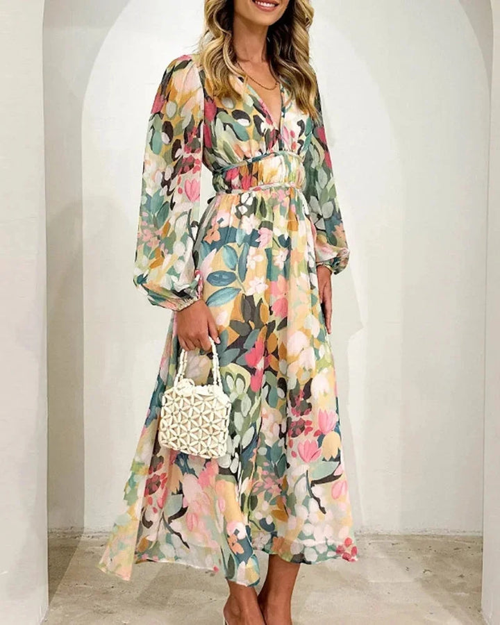 Robe longue fleurie à manches longues en tissu fluide, col en V et taille cintrée, idéale pour un mariage au printemps.