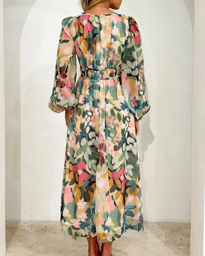 Robe longue fleurie en tissu fluide, col en V et manches longues, avec taille cintrée, parfaite pour un mariage au printemps.
