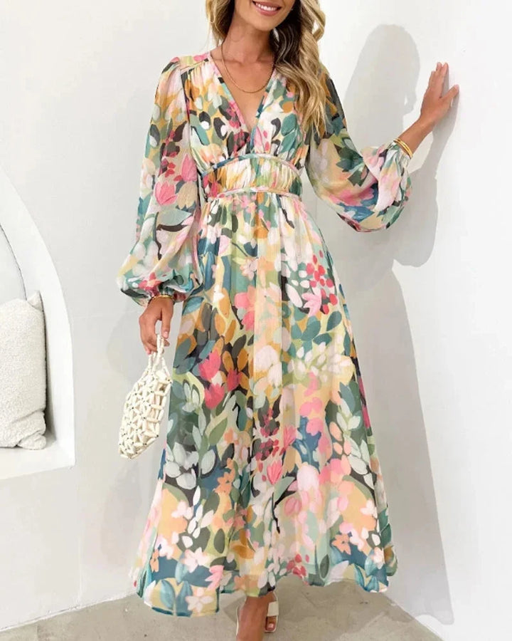 Robe longue fleurie à manches longues, col en V, en tissu fluide avec taille cintrée, idéale pour un mariage au printemps.