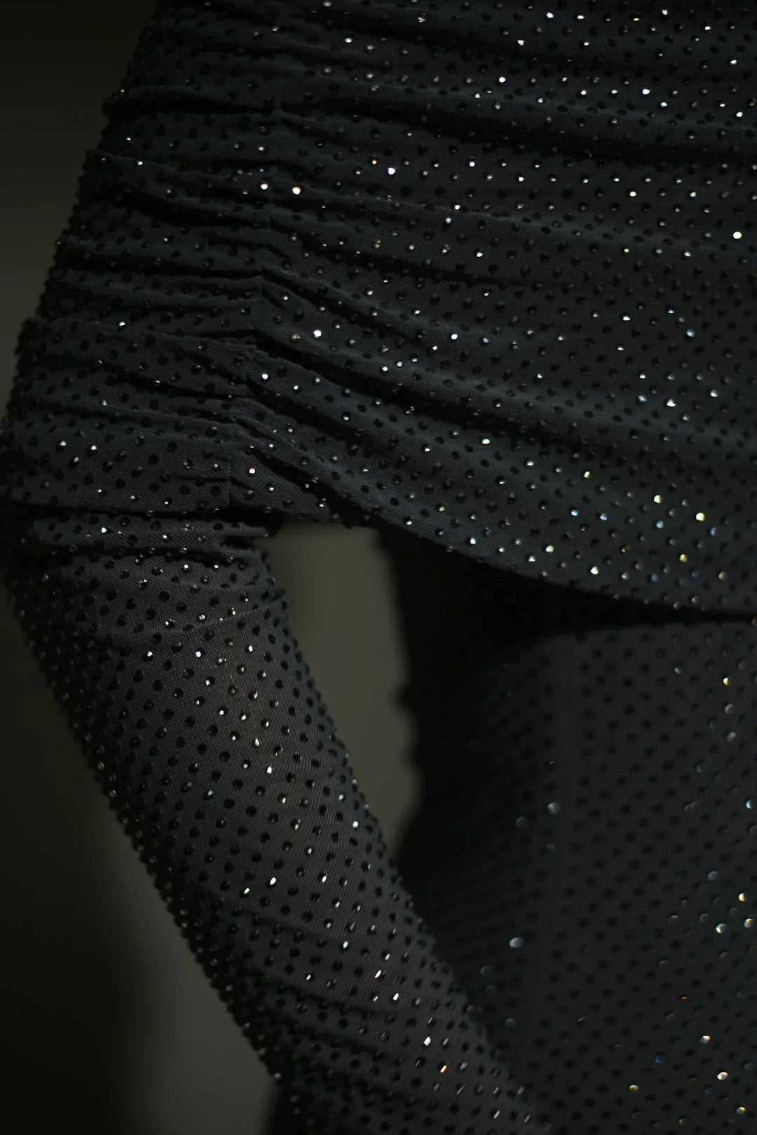 Robe longue longue scintillante avec épaules dénudées, manches longues et détails brillants en tissu léger et fluide.