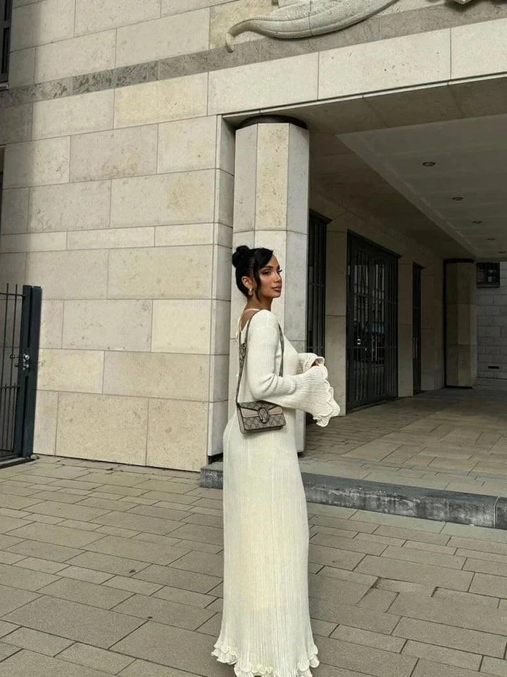 Robe longue plissée avec manches longues évasées, col rond et tissu texturé, parfaite pour une soirée élégante.