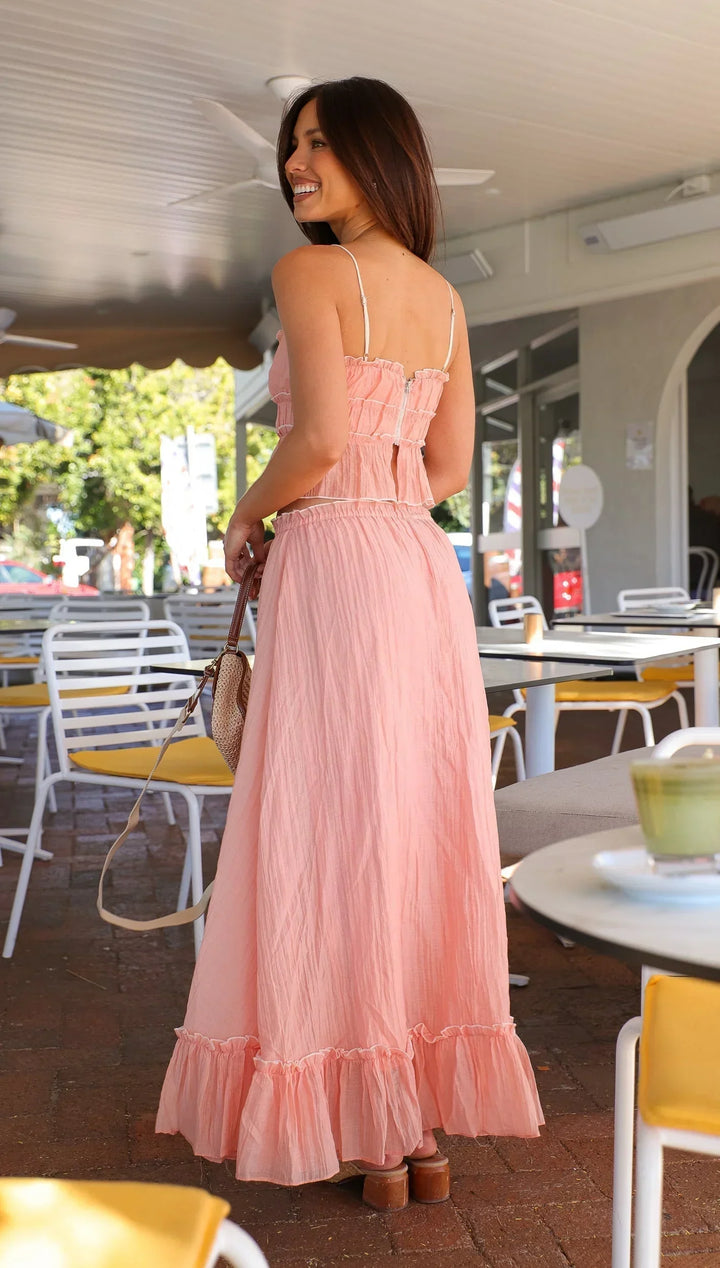 Robe longue rose à volants en coton léger, avec des liens ajustables et un design fluide pour l’été.