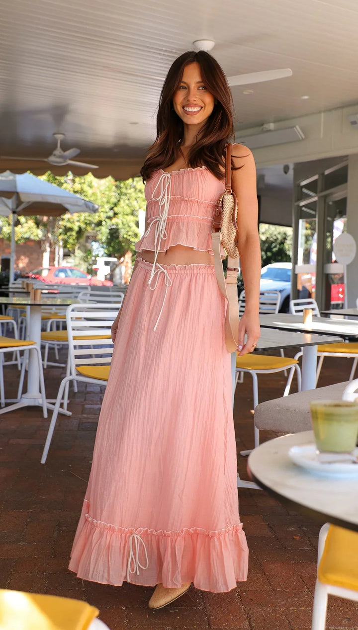 Robe longue rose à volants avec liens, en coton léger, parfaite pour l'été avec une coupe fluide et des détails délicats.