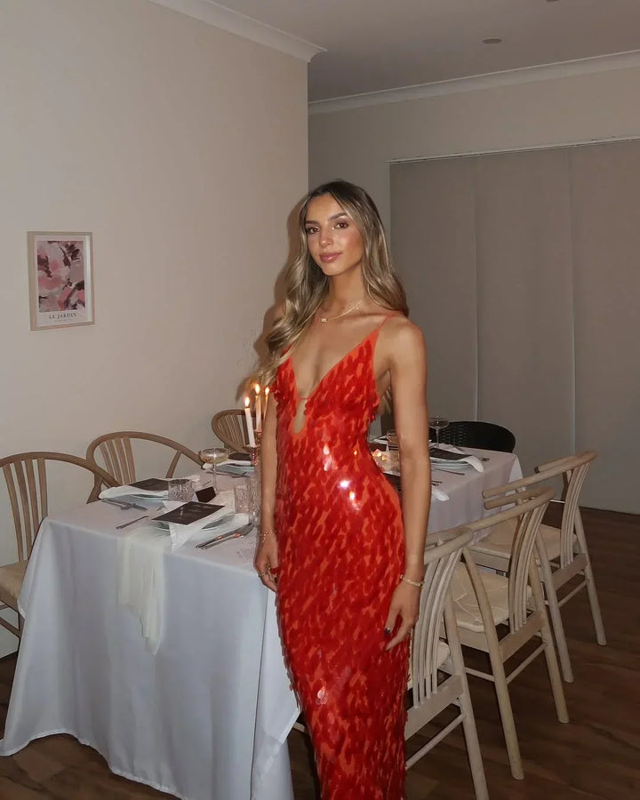 Robe longue rouge à sequins, décolleté plongeant, sans manches, idéale pour les soirées. Matière brillante et ajustée.