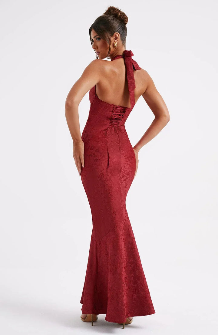 Robe longue rouge avec col licou, nœud à la taille, en tissu fluide avec une texture élégante, idéale pour les soirées.