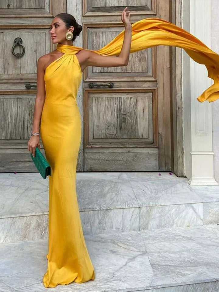 Robe longue satinée à une épaule avec cape, offrant une coupe élégante et un tissu doux au toucher.