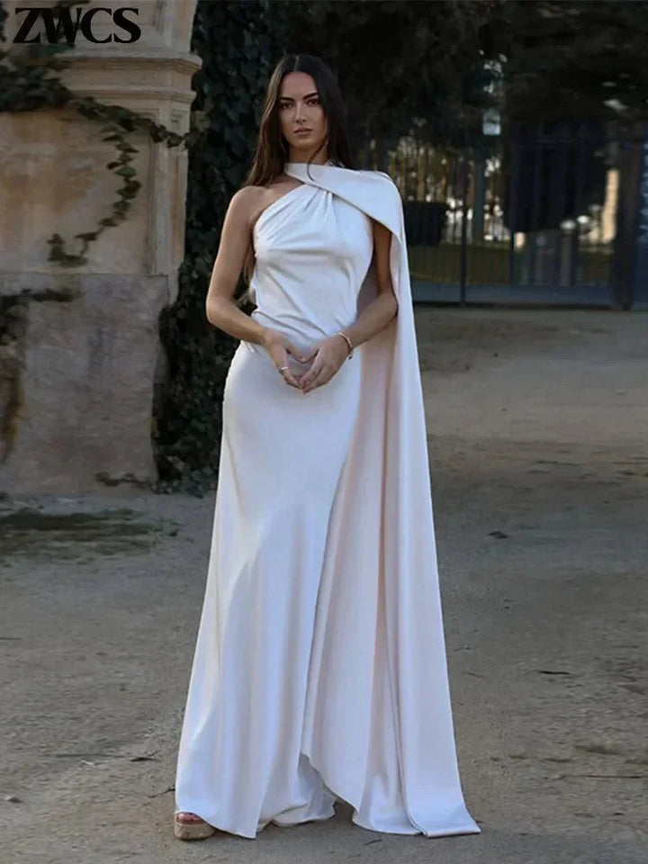 Robe longue satinée à une épaule avec cape, tissu fluide et détails élégants pour une soirée chic.