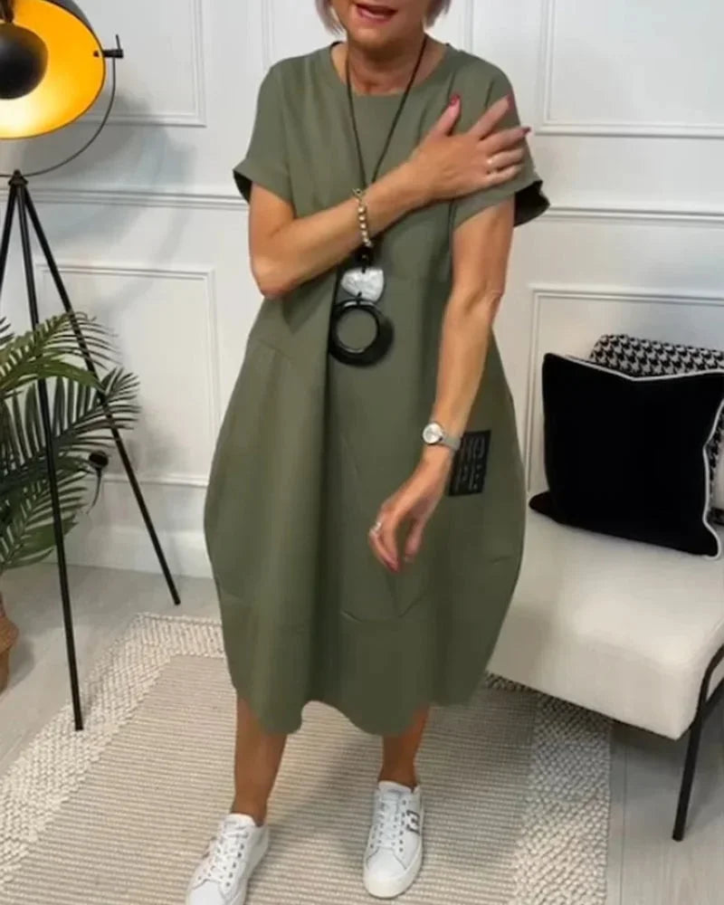 Robe midi ample en tissu fluide, manches courtes et poches, idéale pour un look décontracté en toute saison.