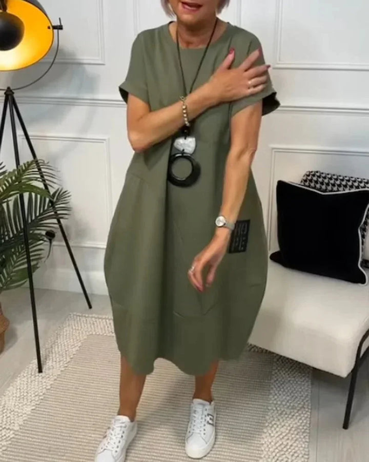 Robe midi ample en tissu fluide, manches courtes et poches, idéale pour un look décontracté en toute saison.