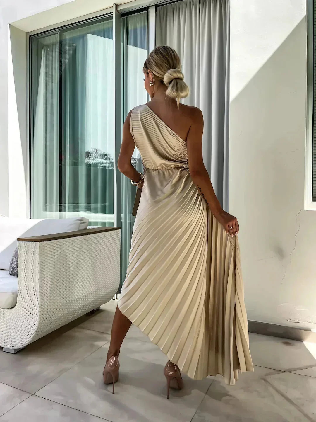 Robe midi plissée asymétrique en polyester, avec découpe stylisée et teinte rose douce. Idéale pour occasions habillées.