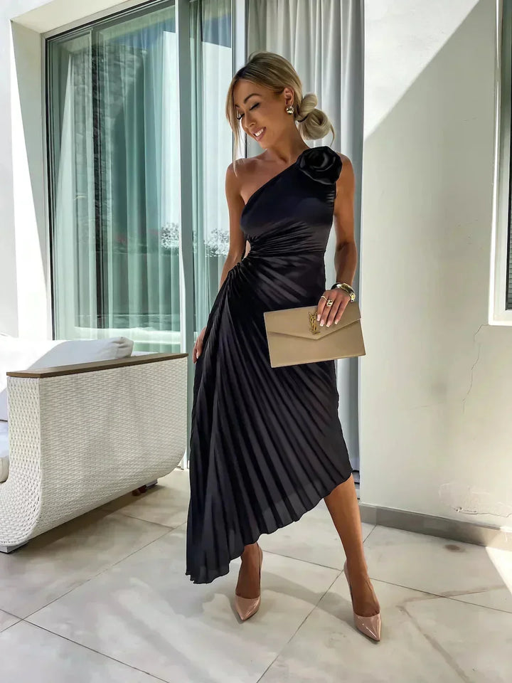 Robe midi asymétrique en noir, plissée avec découpe unique, confectionnée dans un tissu léger et fluide.