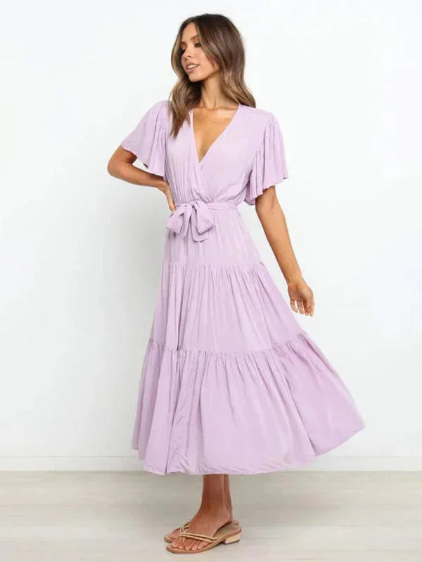 Robe midi fuchsia ceinturée, volants délicats, col en V et manches courtes, en tissu léger pour un look estival.