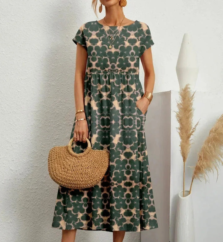 Robe midi verte en coton avec imprimé floral, dotée de poches pratiques et de manches courtes.