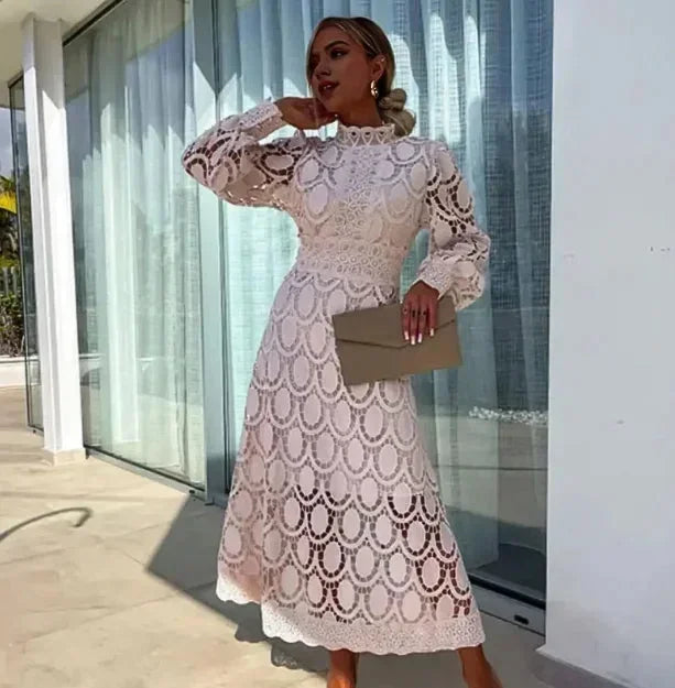 Robe midi blanche en dentelle, manches longues, avec un design élégant et ajouré, parfaite pour les occasions spéciales.