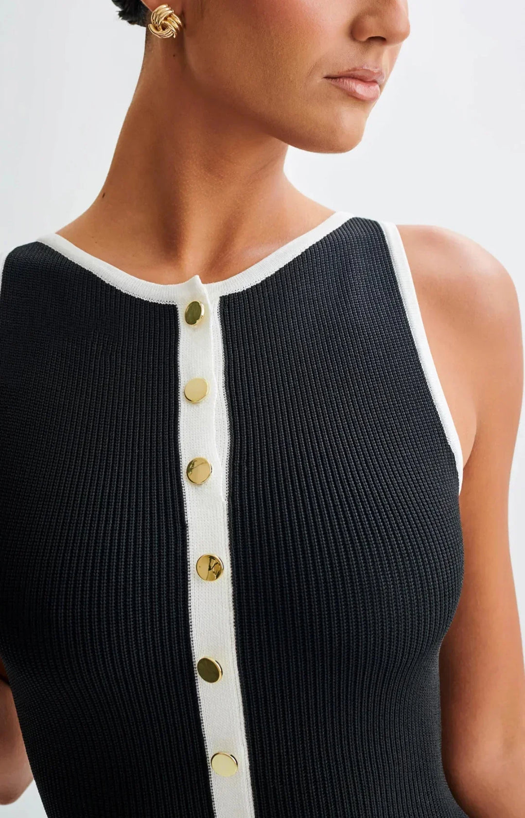 Robe midi noire en coton avec boutons contrastés sur le devant, manches courtes et taille cintrée pour un look élégant.