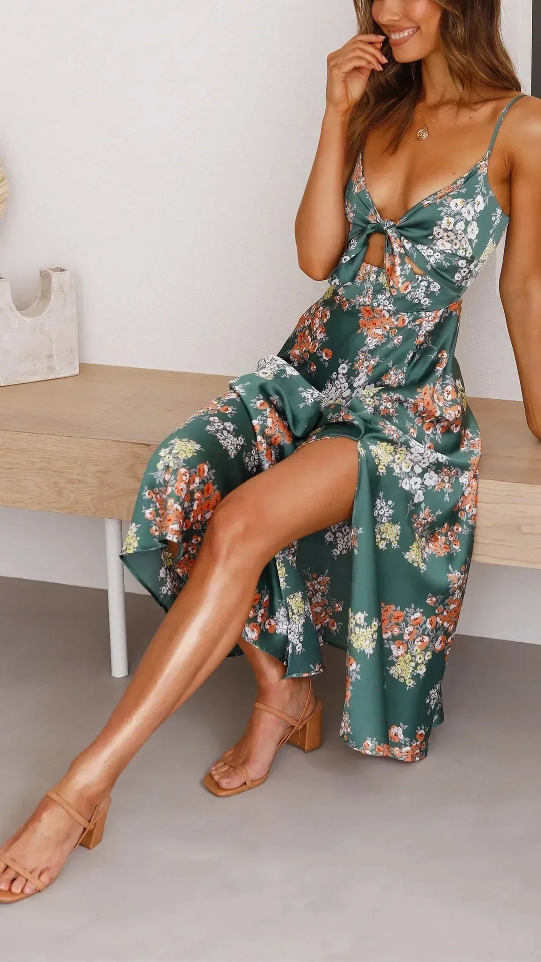 Robe midi fleurie en satin vert avec nœud devant, bretelles fines et design décontracté pour l'été.