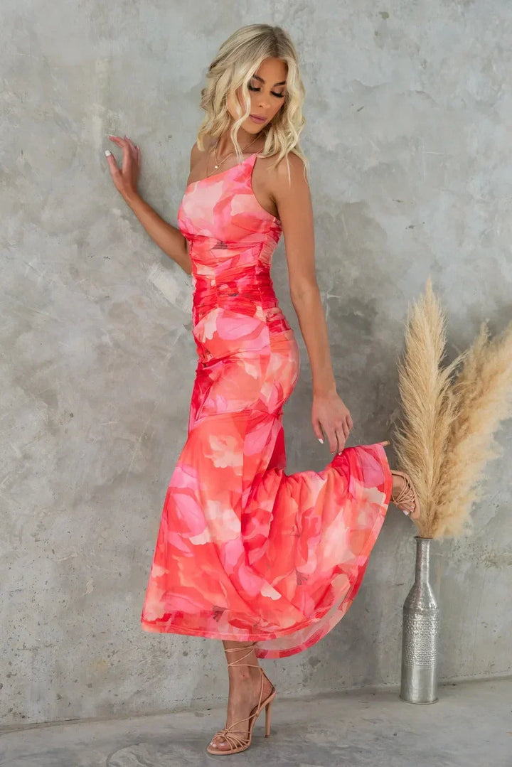 Robe midi florale sans bretelles en tissu fluide, avec un dos asymétrique, parfaite pour un mariage d'été.