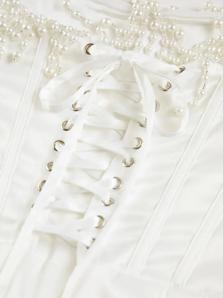 Robe midi ivoire en satin, bustier perlée et corset ajusté, idéale pour des soirées cocktails élégantes.