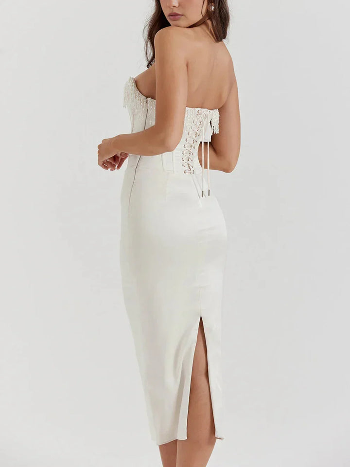 Robe midi ivoire à bustier perlée, corset intégré, tissu léger et fluide, idéale pour soirées et cocktails élégants.