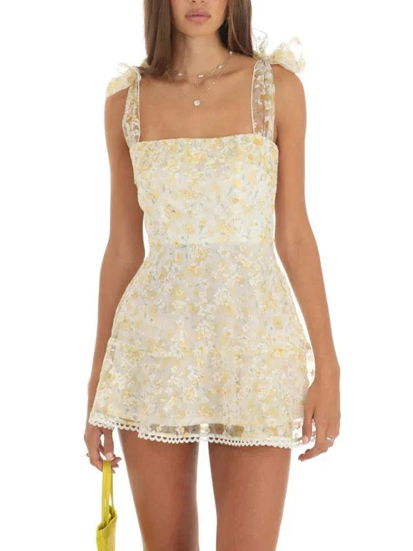 Robe courte A-ligne en tissu léger, détails en dentelle délicate et nœuds sur les épaules, idéale pour une soirée d'été.