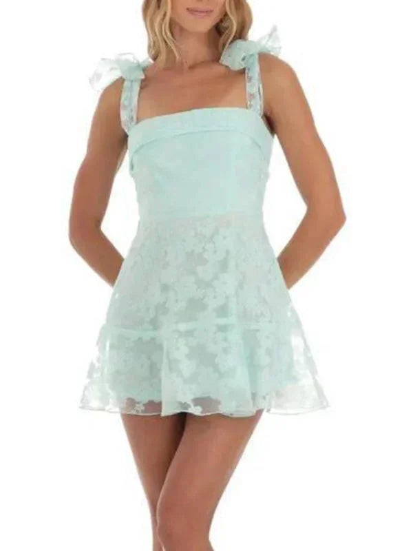 Robe courte A-ligne en coton léger, avec dentelle délicate et nœuds aux épaules, idéale pour des soirées estivales.