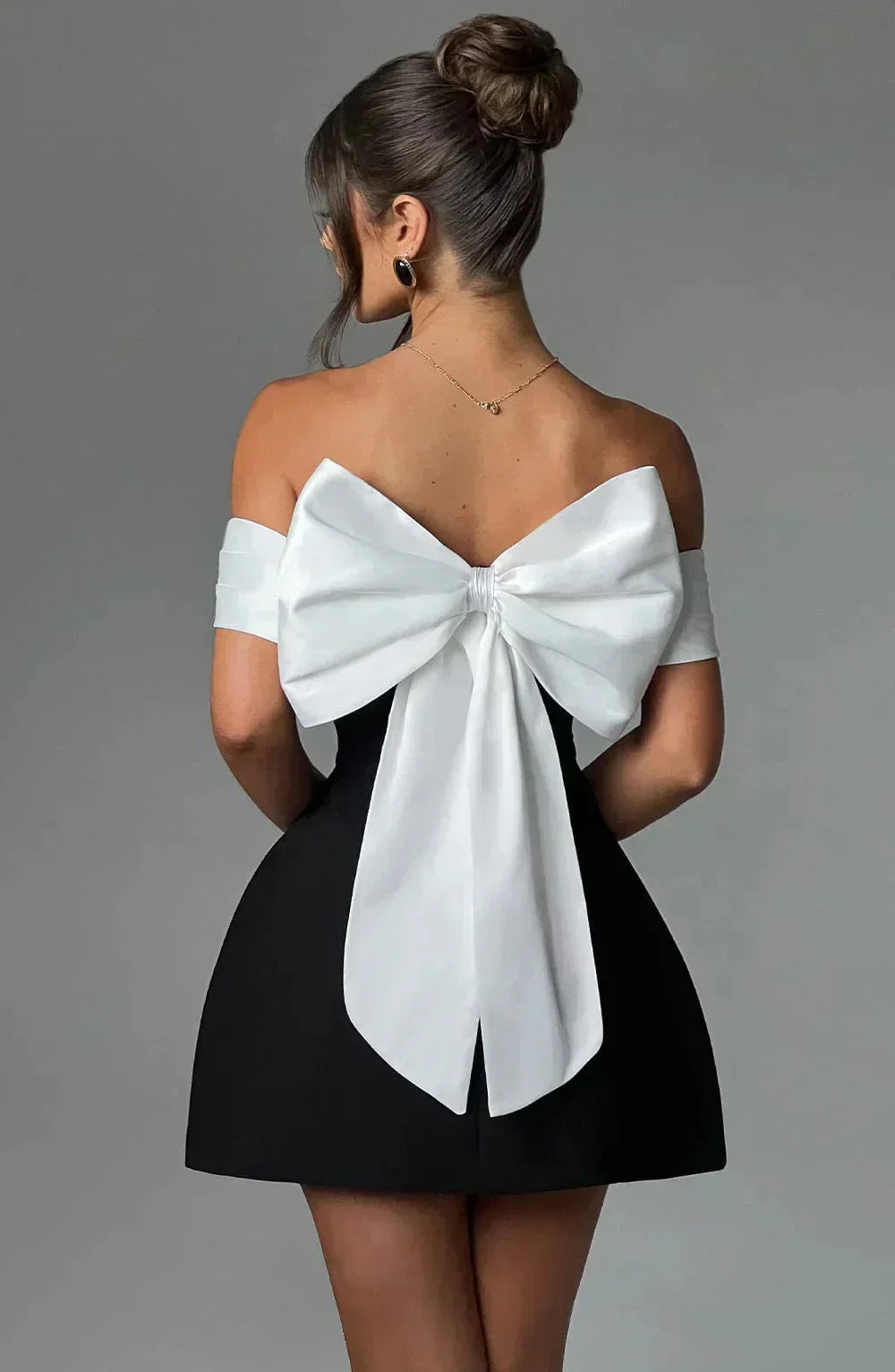 Robe courte bicolore avec épaules dénudées, nœud blanc, en tissu léger, idéale pour les soirées élégantes.