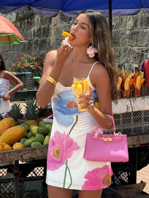 Robe courte blanche avec motifs floraux colorés, en coton léger, bretelles fines, idéale pour l'été à la plage.