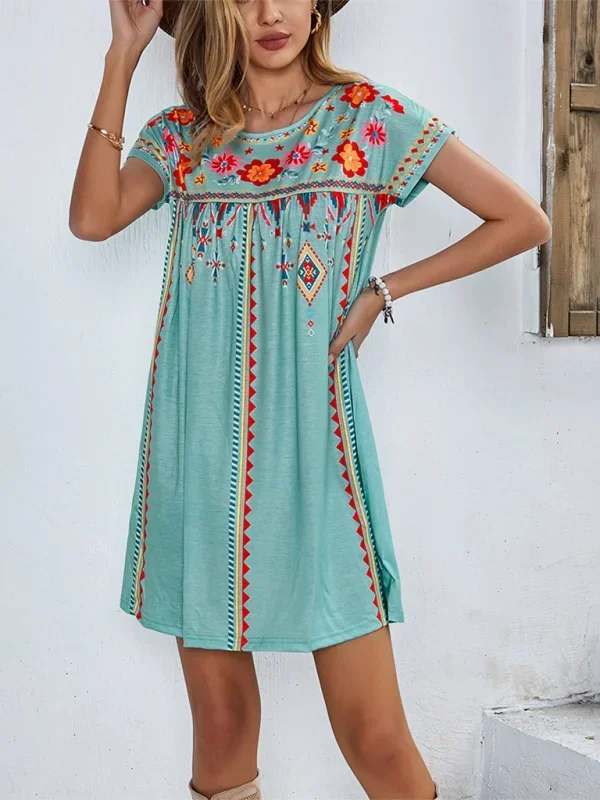Robe courte bohème légère en tissu brodé, manches courtes, motifs floraux pour un look estival à la plage.